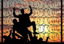 Silhouette of people helping each other over fence