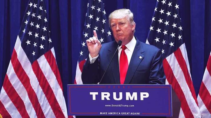 1456399979 featured image Man speaking at podium with USA flags behind him.