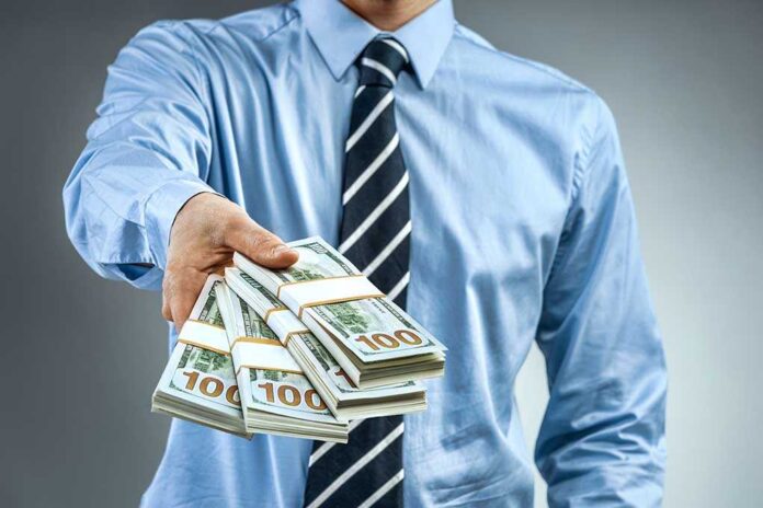 1008204853 featured image Person handing over a stack of money.