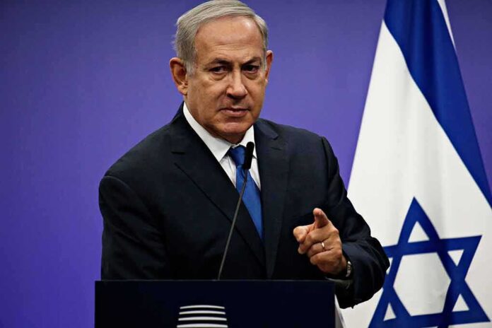 Man speaking at podium with Israeli flag behind him