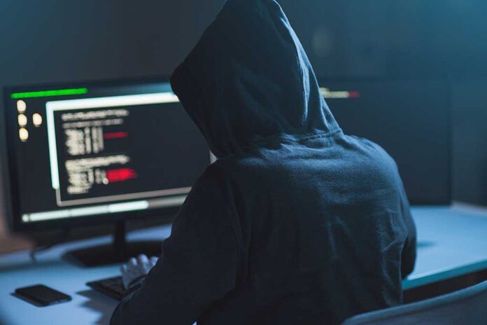 1083511010 featured image Person in hoodie using computer with code on screen.