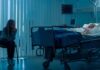 Woman sitting beside hospital bed at night