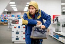 Person in store, hiding something in a bag.