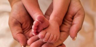 Adult hands holding baby feet gently