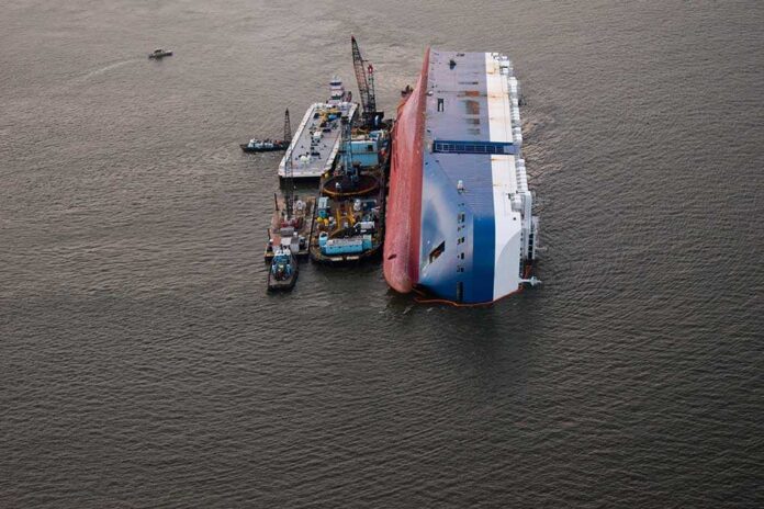 1540854386 featured image Capsized ship with cranes and tugboats around it