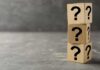 Three wooden blocks with black question marks stacked