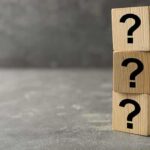 Three wooden blocks with black question marks stacked