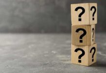 Three wooden blocks with black question marks stacked