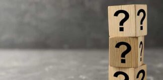 Three wooden blocks with black question marks stacked