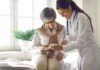 Doctor showing phone to a smiling elderly woman