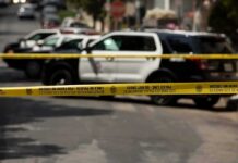 Police tape blocking street with patrol cars