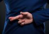 Person crossing fingers behind their back in suit