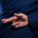 Person crossing fingers behind their back in suit