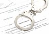 Handcuffs on top of an arrest warrant document