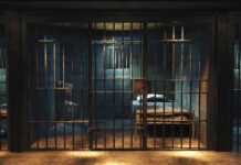 Empty prison cell with metal bars and bed