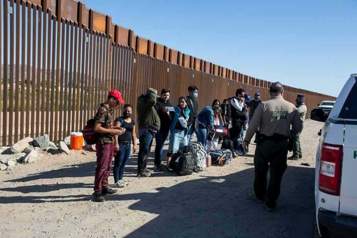 Group of people at border wall with patrol agents