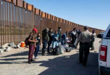 Group of people at border wall with patrol agents