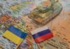 Toy tank on map with Ukraine and Russia flags.