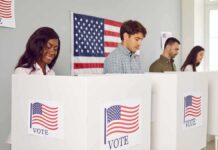 People voting in booths with American flag backdrop