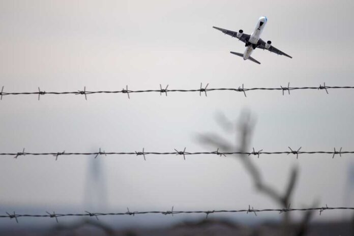 2401451327 featured image Airplane ascending above barbed wire fence sky background
