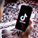 TikTok Chaos: Trump Triggers App Meltdown Hand holding phone showing TikTok logo