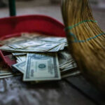Budget BOMBSHELL: $48 Billion Vanishes Overnight Broom sweeping dollar bills into red dustpan floor