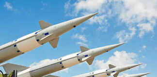 Multiple missiles pointed upward on launchers against blue sky