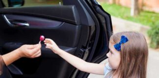 Child receiving lollipop from person in open car