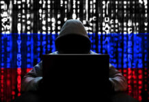 Hacker in hoodie with Russian flag background and code