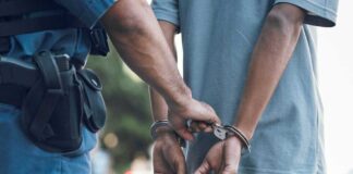 Police officer handcuffing a persons hands behind back