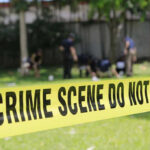 Yellow crime scene tape blocking grassy area