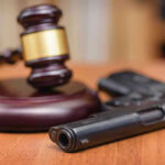 11th Circuit STINGS: Gun Rights Triumph Gavel and handgun on a wooden surface.