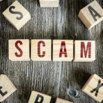 AI Scam Wipes Out $1 Billion—FBI Alarmed Wooden blocks spell SCAM on a rustic surface.