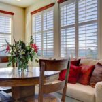 Ancient Wisdom Finally Released – Home Miracles Cozy dining area with a round table, flower arrangement, and comfortable seating by the window