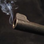$11B NY Contract—Smoking Gun Reveals Scandal Close-up of a gun barrel emitting smoke against a black background