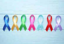 Colorful awareness ribbons on light wooden background