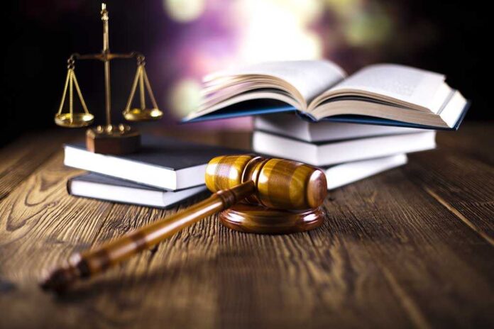 A gavel, legal books, and scales of justice on a wooden table