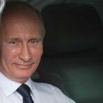 Is This Proof That Putin Assassinated Navalnaya? A smiling man in formal attire sitting inside a car with curtains