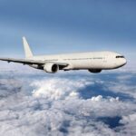 Avoid These Travel Booking Sites – BUSTED for Deception A white airplane flying above fluffy clouds in a blue sky
