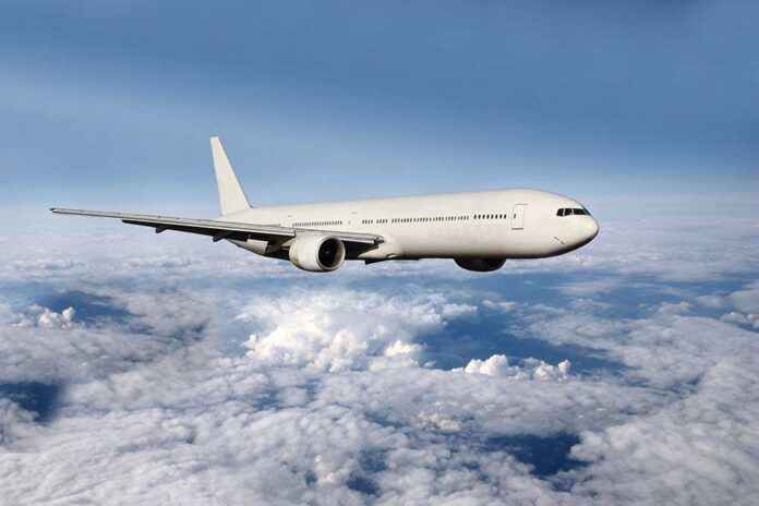 A white airplane flying above fluffy clouds in a blue sky