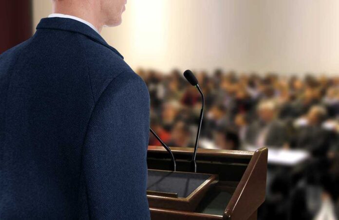 A speaker at a podium addressing an audience
