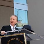 Left-Wing Critics SLAM Maher Over Free Speech Stand A man in formal attire speaking at a podium during a Hollywood Walk of Fame ceremony