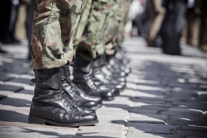Row of soldiers in camouflage pants standing in formation with black boots