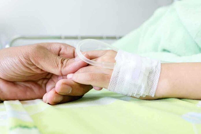A person holding the hand of a patient with an IV in a hospital bed