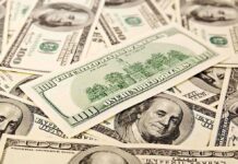 A collection of hundred dollar bills scattered on a surface