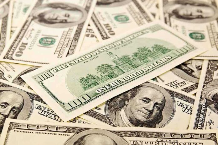 A collection of hundred dollar bills scattered on a surface