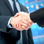 Two business professionals shaking hands in a corporate setting