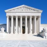 The Supreme Court building featuring marble columns and a clear blue sky