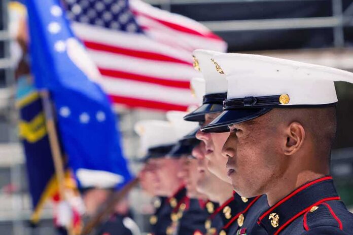 US Marines in uniform standing in formation with flags in the background