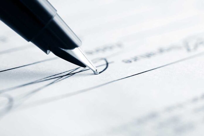Close-up of a pen poised above a document with handwritten lines